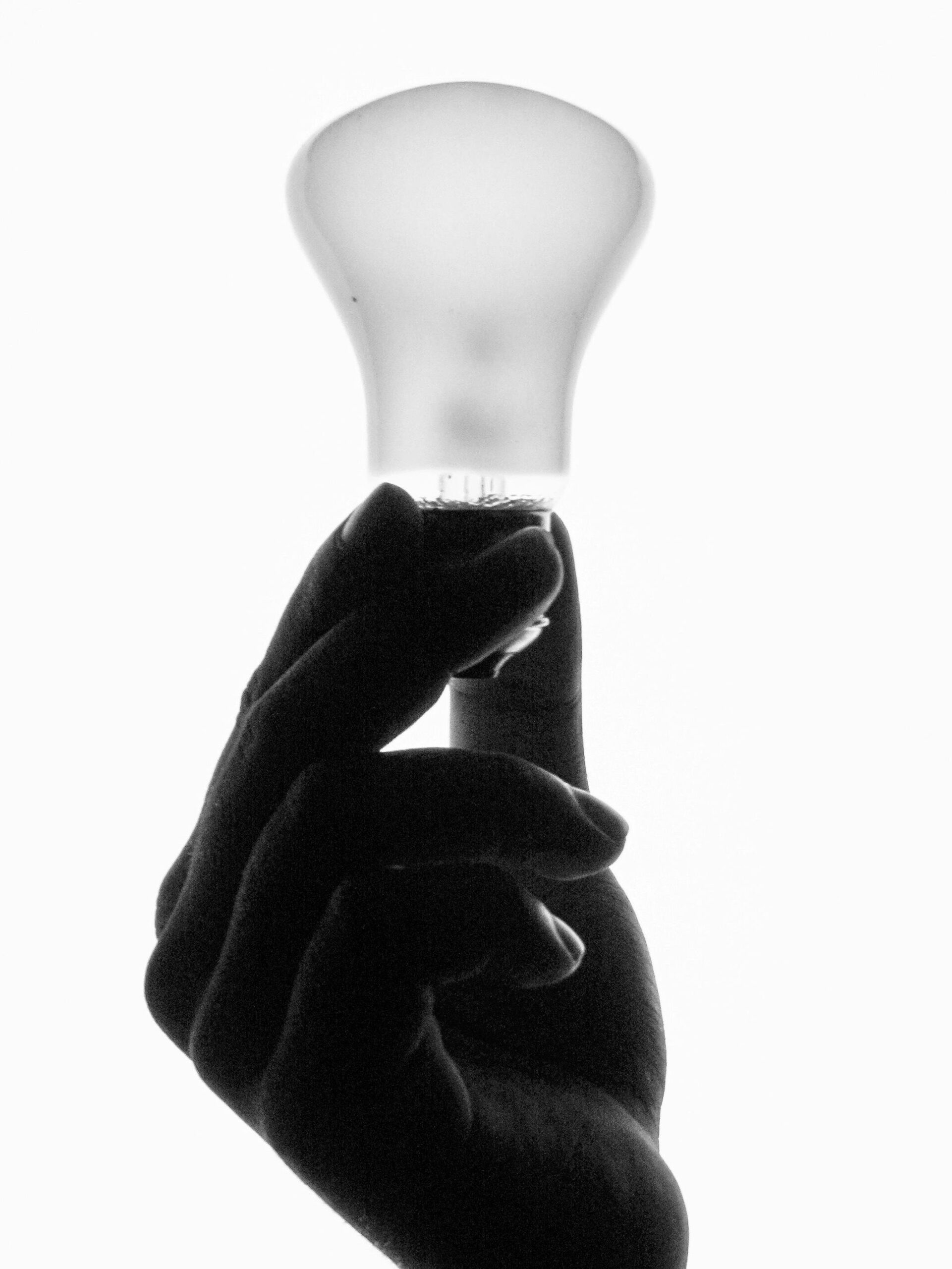 A conceptual grayscale image of a hand holding a lightbulb, symbolizing ideas and intelligence.